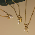 Gold necklaces with charms on a beige surface